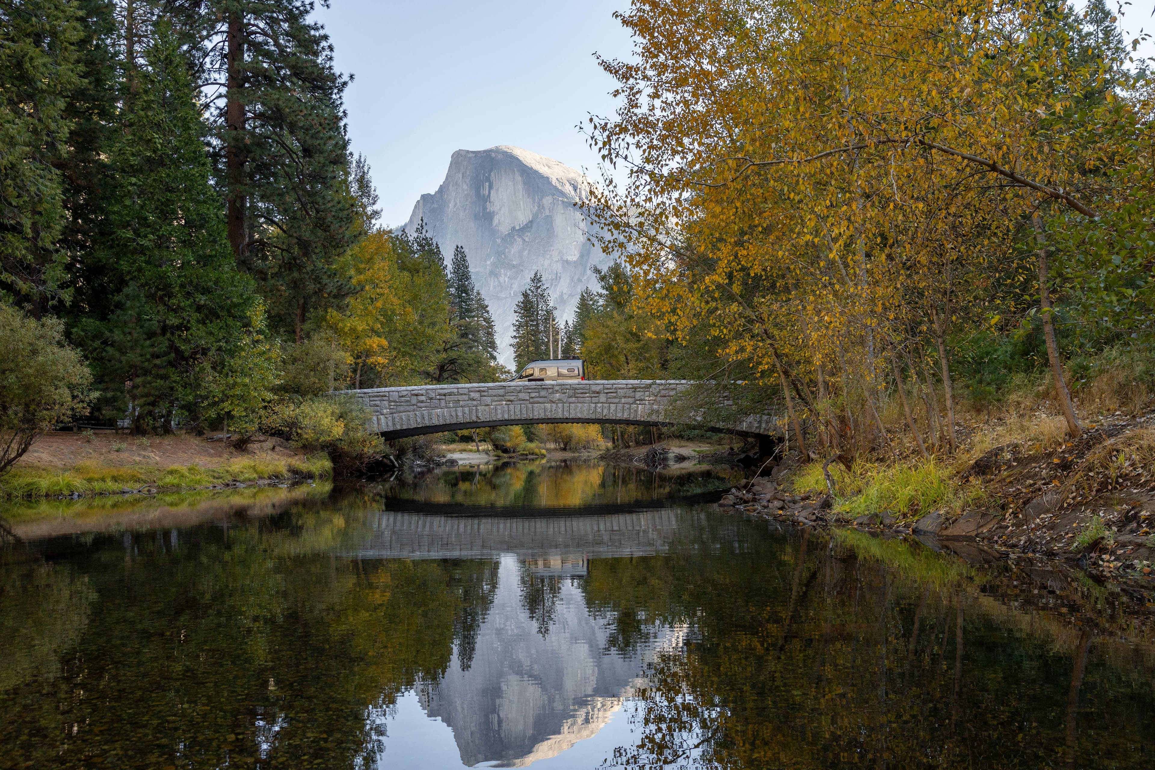 A bridge over a river with trees and mountains in the background